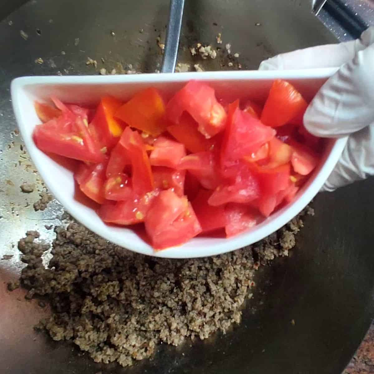 a hand showing tomatoes cut in dice