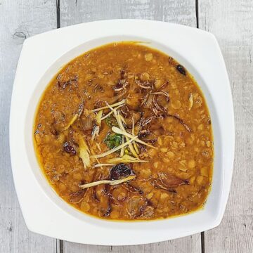 chana daal served in white plate with garnish of ginger and tarka