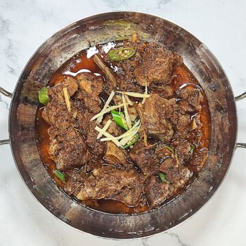 mutton karahi served in bowl with garnish on top