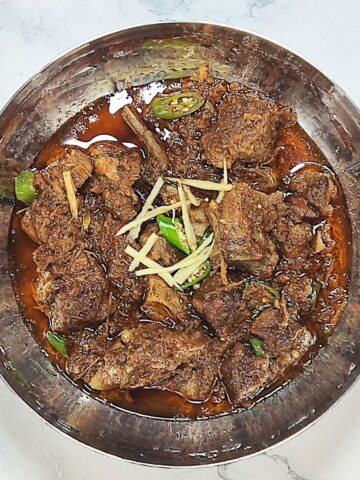 mutton karahi served in bowl with garnish on top