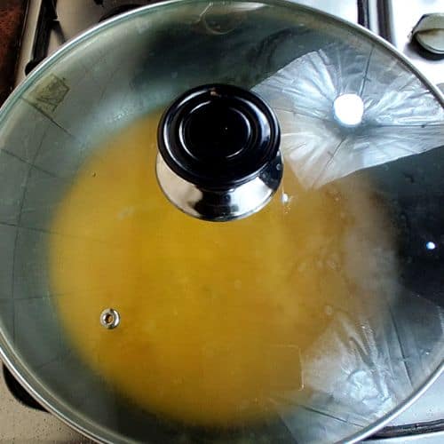 Golden curry base simmering in a stainless steel pot with glass lid during preparation.