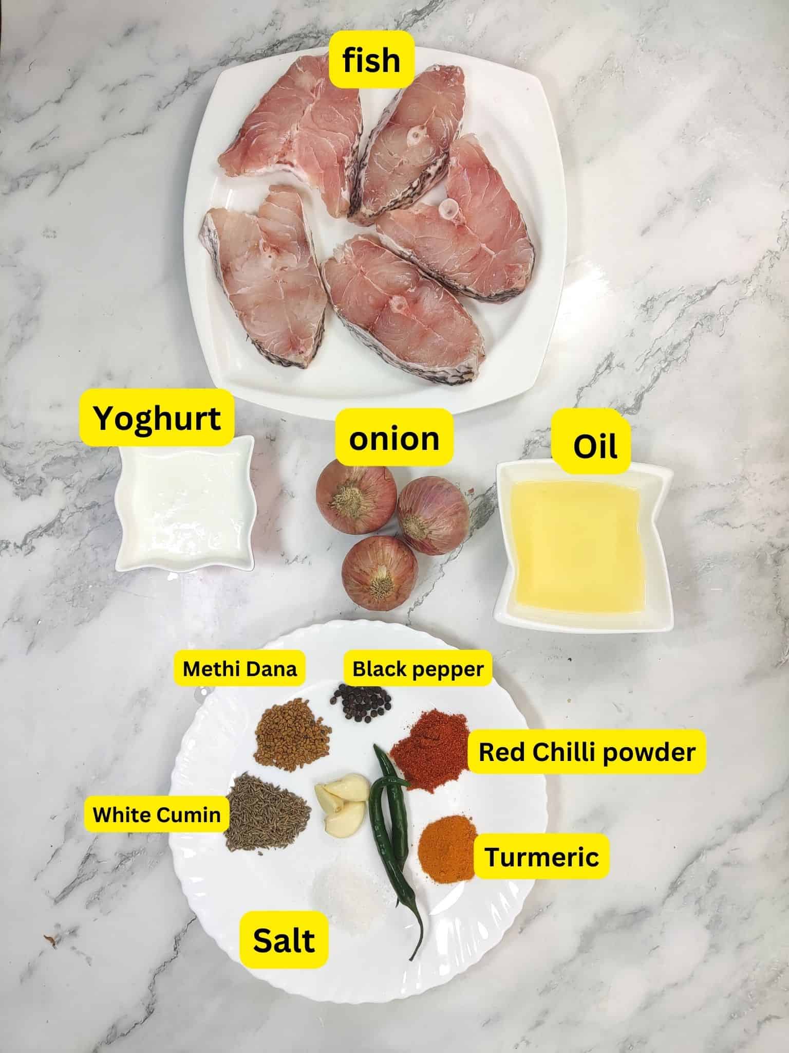 Ingredients for fish curry displayed on marble countertop: raw fish fillets, yogurt, onions, oil, and spices.