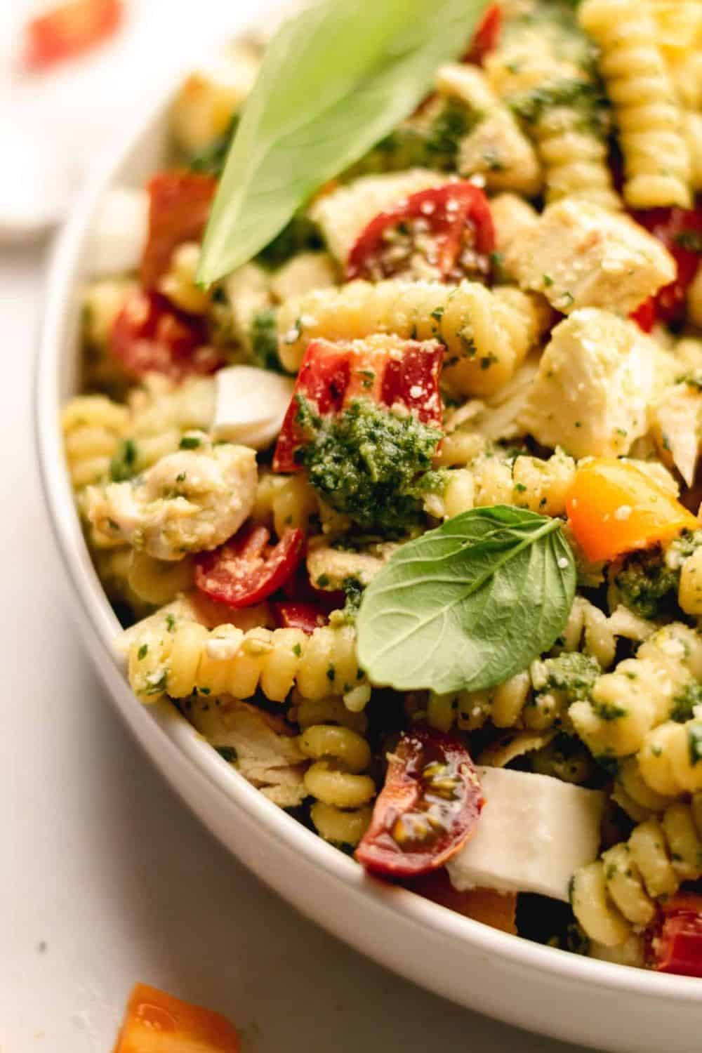 summer pesto chicken pasta salad basil cherry tomatoes mozzarella pine nuts vibrant green sauce picnic potluck Italian