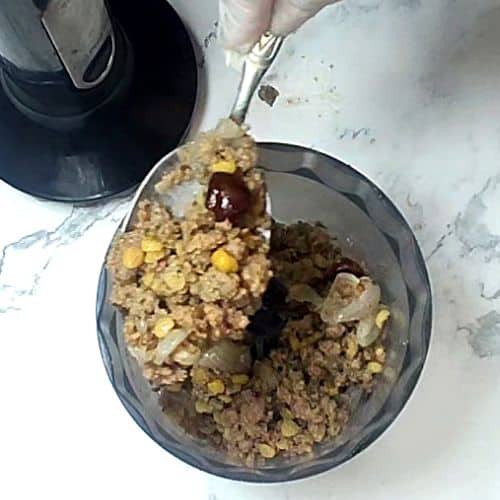 Shami kebab mixture in gray bowl with spoon, showing ground meat and lentil texture.