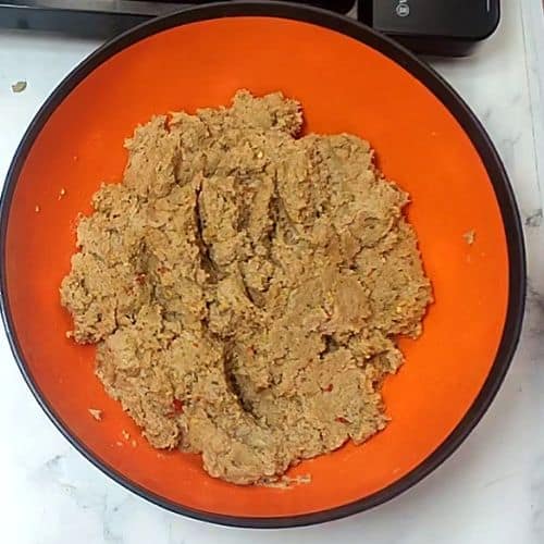 Shami kebab mixture with tan, crumbly texture in orange bowl, ready for cooking.
