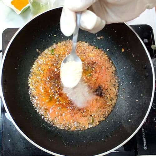 Daal mash being prepared in a black wok with yogurt being stirred in, Pakistani style cooking.