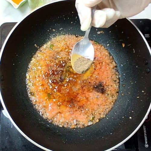 Daal mash cooking in wok with spoon stirring golden-brown lentil mixture.