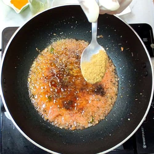 Daal mash cooking in wok with spoon stirring golden-brown lentil mixture.