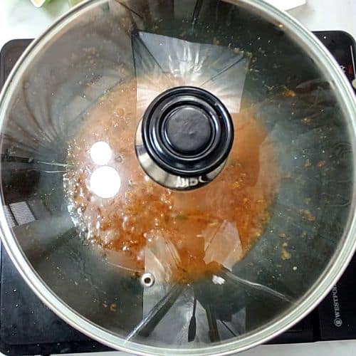 Dal mash cooking in a pressure cooker with lentils at various stages of softening.