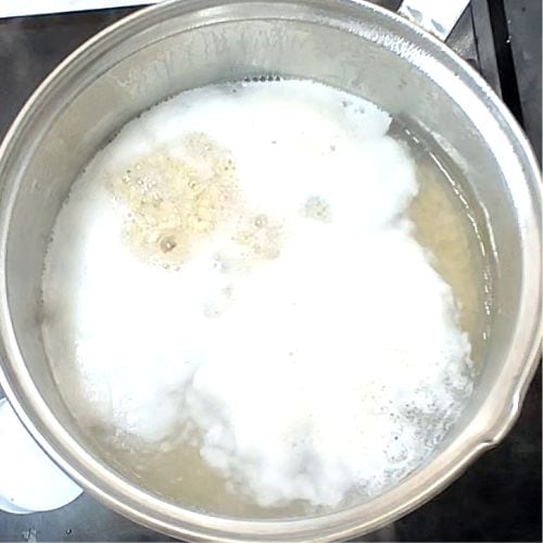 Daal mash simmering in stainless steel pot with white creamy texture and visible spices.