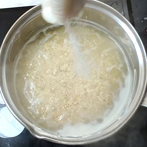 Daal mash being stirred in a clear glass bowl, showing beige-colored lentil paste with a creamy texture.