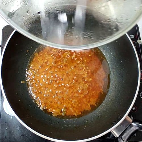Dal mash cooking in a wok with boiling water and bubbling orange lentil mixture.