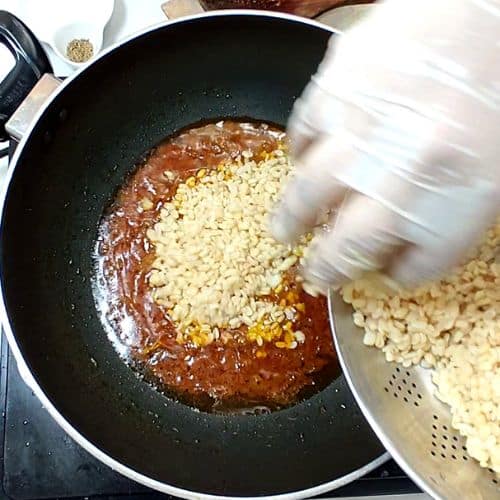 Daal mash being prepared in a wok with cooked lentils being added to spiced tomato base.