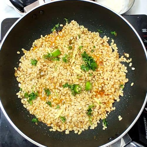 Daal Mash cooking in black wok with green onions and orange carrots scattered throughout.