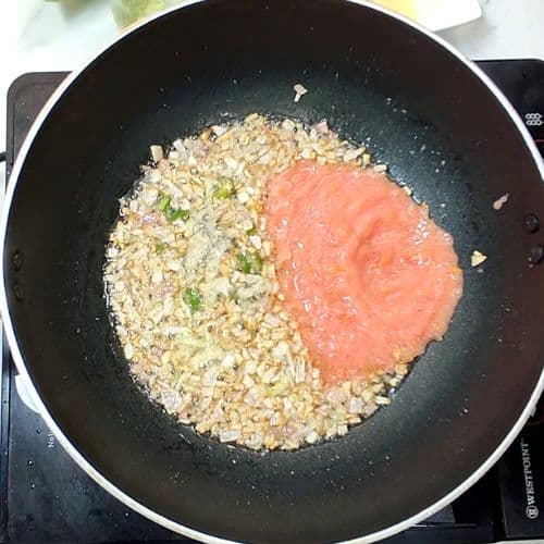 Daal Mash cooking in a wok with tomato paste added to cooked lentils and spices.