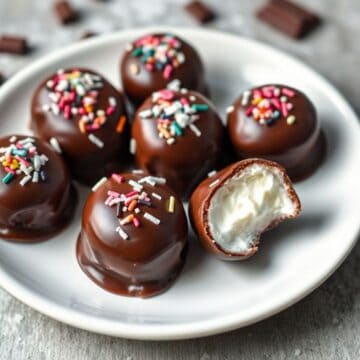 Chocolate-coated Cool Whip candies with colorful sprinkles on white plate, one cut in half.