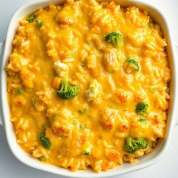 Cheesy chicken and rice casserole in white baking dish with melted cheese and broccoli florets.