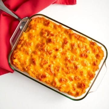 Cheesy hash brown casserole in glass baking dish with golden-brown melted cheese topping.