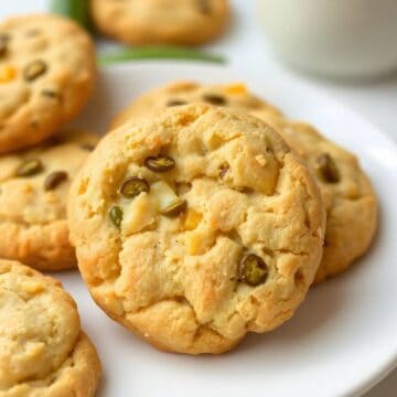Cheesy jalapeño shortbread cookies with melted cheese and green pepper pieces on white plate.
