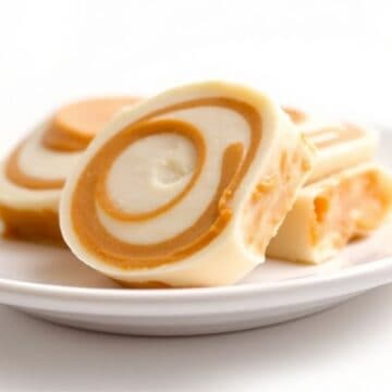 Old-fashioned potato candy slices with caramel swirl displayed on white plate.