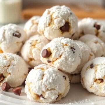 Peanut butter chocolate chip snowball cookies dusted with powdered sugar on a white plate.