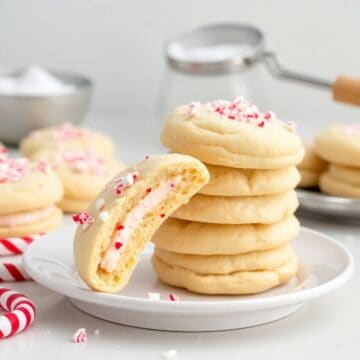 Peppermint cheesecake cookies with red and white candy pieces on white plate with peppermint candies.