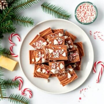 Delicious homemade Christmas fudge topped with crushed peppermint candies and white chocolate pieces.