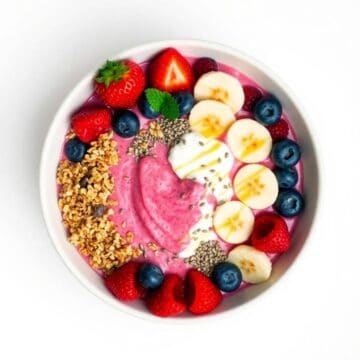 Vibrant smoothie bowl topped with fresh strawberries, bananas, blueberries, and granola. Perfect for.