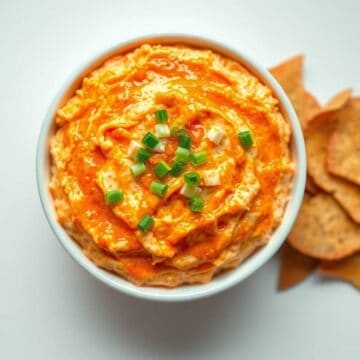 Delicious buffalo chicken dip garnished with green onions in a white bowl. Perfect appetizer for par.