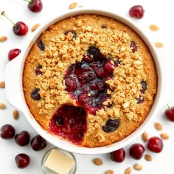 Delicious cherry dump cake with berries and crumb topping in a white baking dish.