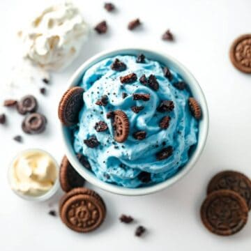Blue cookie-flavored ice cream with Oreo chunks and cookie pieces in a bowl.