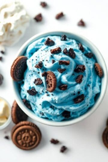 Blue cookie-flavored ice cream with Oreo chunks and cookie pieces in a bowl.