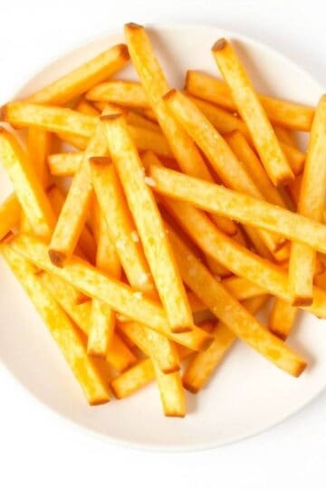 Golden French fries served on a white plate, perfect for snacking or as a side dish.