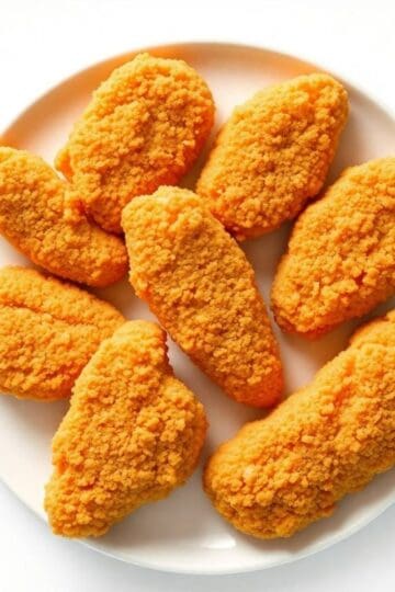 Crispy fried chicken tenders on a white plate, perfect for a delicious meal.