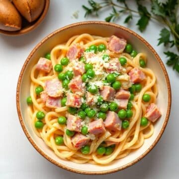 Delicious ham and green peas pasta dish with grated cheese, perfect for a quick meal.