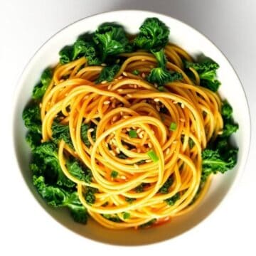 Sesame kale noodles with green onions in a white bowl, healthy Asian-inspired dish.