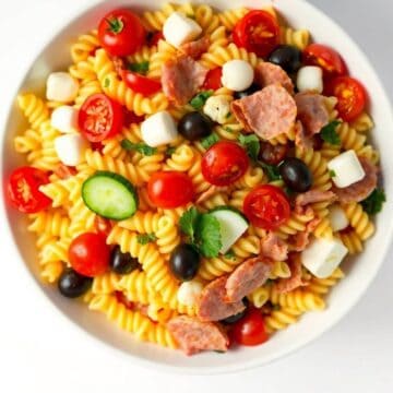 Colorful antipasto pasta salad with cherry tomatoes, mozzarella, olives, and cured meats.