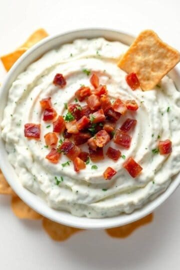 Delicious bacon ranch dip garnished with crispy bacon bits and fresh herbs, perfect for parties and.