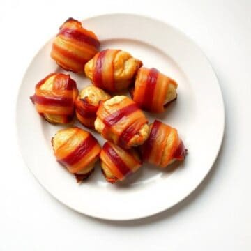 Delicious bacon-wrapped chicken bites on a white plate, perfect appetizer.