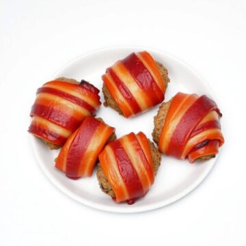 Bacon-wrapped mini meatloaf bites on a white plate, perfect for appetizers or party snacks.