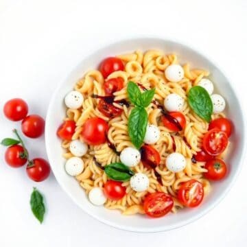 Fresh Caprese pasta salad with cherry tomatoes, mozzarella balls, and basil leaves.
