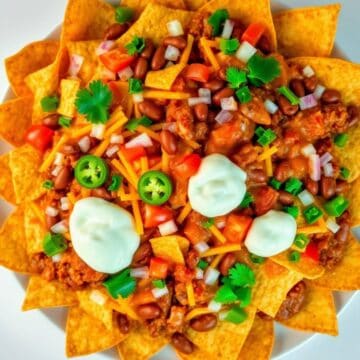 Delicious chili cheese nachos topped with jalapeños, cilantro, and sour cream.