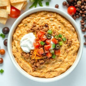 Delicious taco dip with cheese, tomatoes, and sour cream in a bowl.
