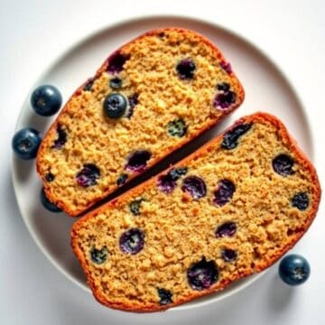 Blueberry zucchini bread with fresh blueberries and shredded zucchini on a white plate.