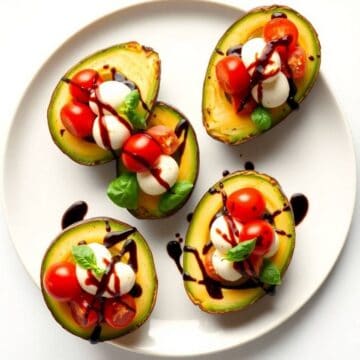 Caprese stuffed avocados with cherry tomatoes, mozzarella, basil, and balsamic glaze.