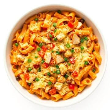 Delicious creamy chicken pasta casserole with vegetables and cheese in a white bowl.