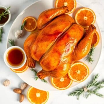 Juicy roasted chicken glazed with orange and maple syrup, garnished with fresh orange slices.
