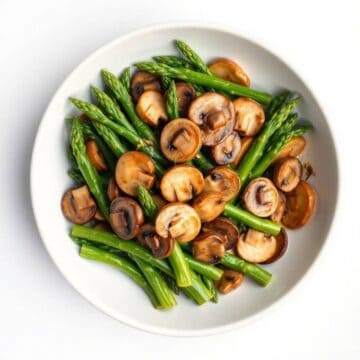Sautéed asparagus and mushrooms on a white plate, highlighting fresh green asparagus and brown mushr.