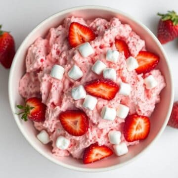 Delicious strawberry fluff salad topped with fresh strawberries and mini marshmallows. Perfect for s.