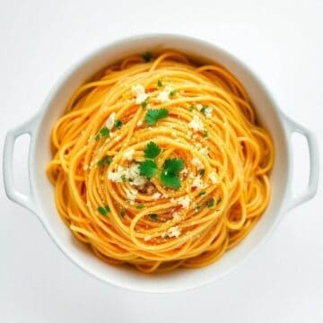 Delicious baked lemon spaghetti garnished with herbs and cheese in a white dish.